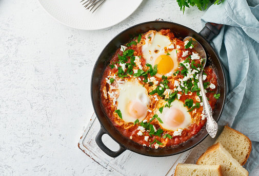 Shakshouka, eggs poached in sauce of tomatoes, olive oil, peppers, onion and garlic, Mediterranean cuisine. Keto meal, FODMAP recipe, low carb. Top view, copy space