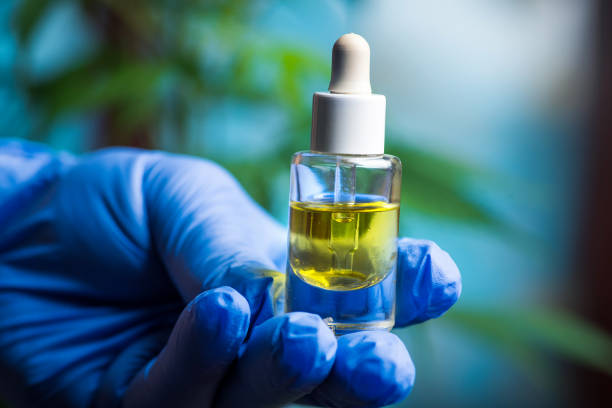 Scientist holding cannabis marijuana oil in a small jar close up Medical research scientist holding cannabis marijuana oil in a small jar close up with leaves in the background hashish stock pictures, royalty-free photos & images