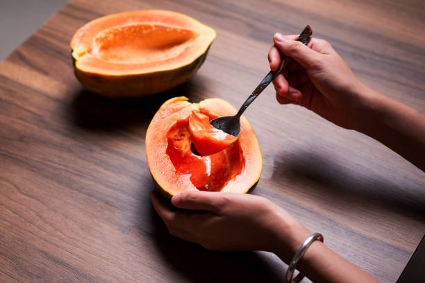 istock Female eating papaya fruit with a spoon top view 1265172013