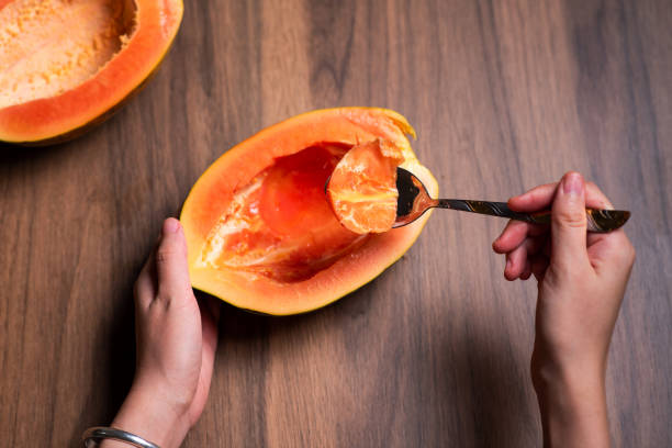 istock Female eating papaya fruit with a spoon top view 1265172025