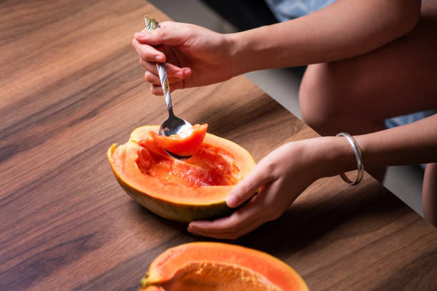 istock Female eating papaya fruit with a spoon top view 1265172038