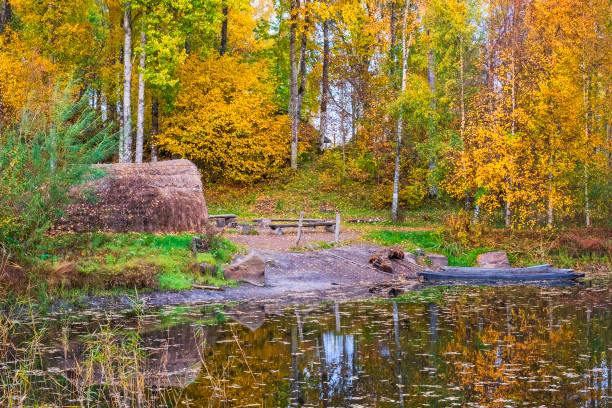 блиндажи каноэ и травяная хижина на лесном озере с осенними цветами - logboat стоковые фото и изображения