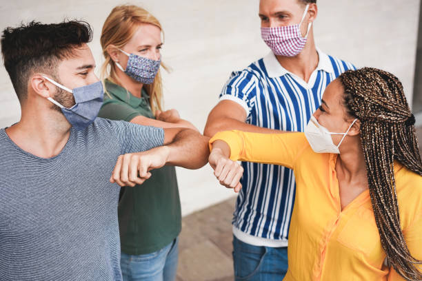 istock Young people friends bump their elbows instead of greeting with a hug - Avoid the spread of coronavirus, social distance and friendship concept - Focus on right woman face 1265173323