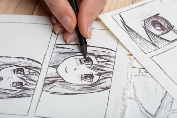 Photo of Artist drawing an anime comic book in a studio.