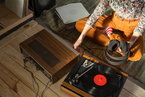 jeune femme écoutant une musique sur un système hifi avec platine, amplificateur, écouteurs et disques vinyle lp dans une salle d’écoute - woman taking radio vintage photos et images de collection