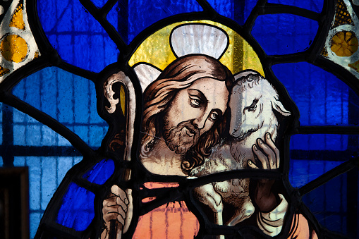 Jesus Christ holding a lamb and shepherd's crook depicted in a stained glass window in an English church