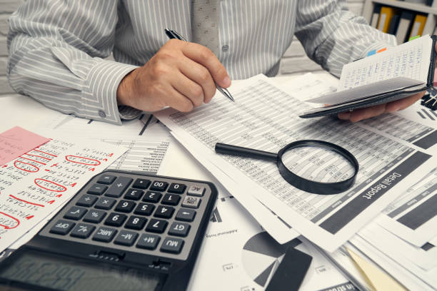 istock Business analysis and accounting concept - businessman working with document, spreadsheet, using calculator, tablet pc. Office desk closeup. 1265181039