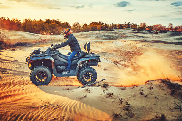 istock Teen riding ATV in sand dunes making a turn in the sand 1265181237