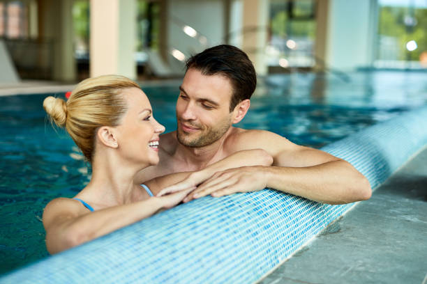 istock Happy couple talking while enjoying in swimming pool at at he spa. 1265181413