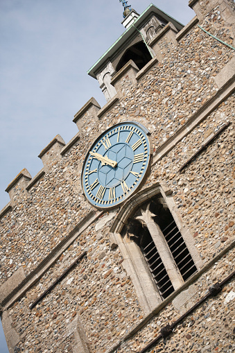 Blue clock face reading 10.55 on a church tower viewed from a low angle