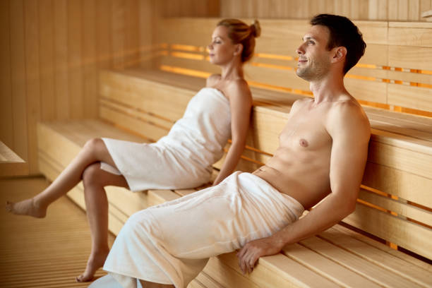 Serene couple relaxing in sauna while spending their weekend at health spa. Focus is on man.