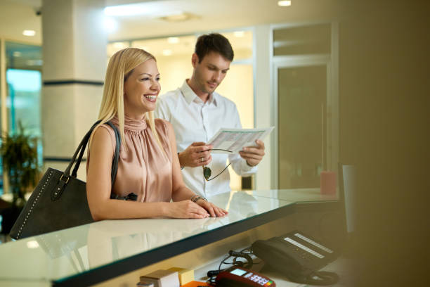 istock Happy couple checking in a hotel at reception desk. 1265183588