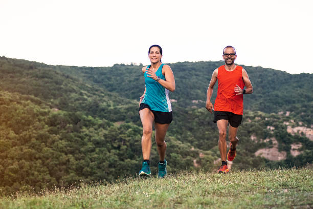 istock Healthy young couple running on mountain trail. 1265183930