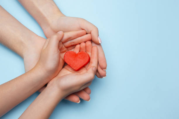 istock Human hands holding, giving heart isolated on blue background 1265185084