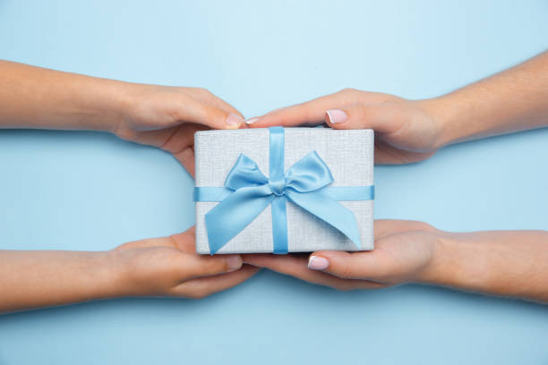 istock Human's hands holding a present, gift, surprise box isolated on blue background 1265185087