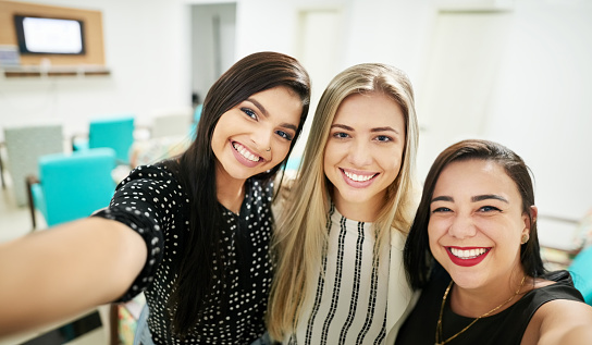 Shot of three businesswomen standing together in conference room taking a selfie
