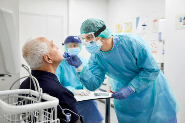 Doctor Taking Coronavirus Sample From Male Patient's Nose Doctor taking coronavirus sample from male patient's nose. Frontline worker is in protective workwear. They are at hospital during epidemic. pcr device photos stock pictures, royalty-free photos & images