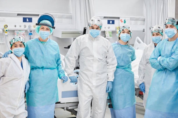 Healthcare Coworkers Standing in ICU During Pandemic Healthcare coworkers standing in ICU. Doctors are wearing protective coveralls. They are at hospital during COVID-19. operating room photos stock pictures, royalty-free photos & images