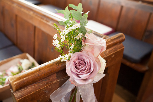 Pink flower decoration on the end of wooden pew in an English church