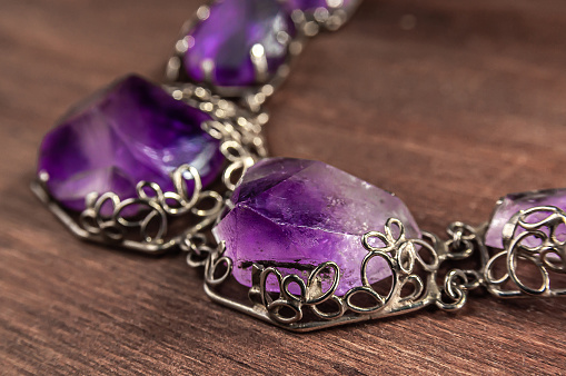 close up of necklace with amethyst on wooden background