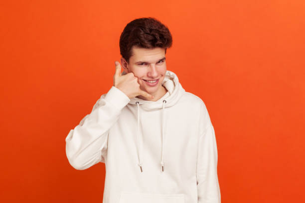 istock Callback. Self confident handsome young man in stylish sweatshirt holding fingers near ear and smiling, high-quality mobile communication, call-centre 1265192012