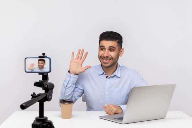 istock Online webinar, distant training. Excited successful businessman sitting at workplace, waving hello 1265192119