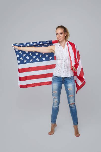 istock blonde woman posing with usa flag in studio on white background 1265193347