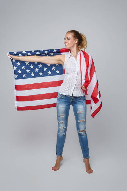 istock blonde woman posing with usa flag in studio on white background 1265193353