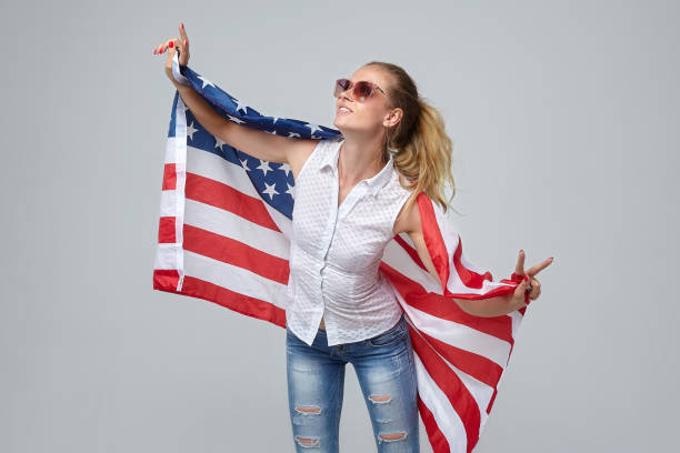 istock blonde woman posing with usa flag in studio on white background 1265193362