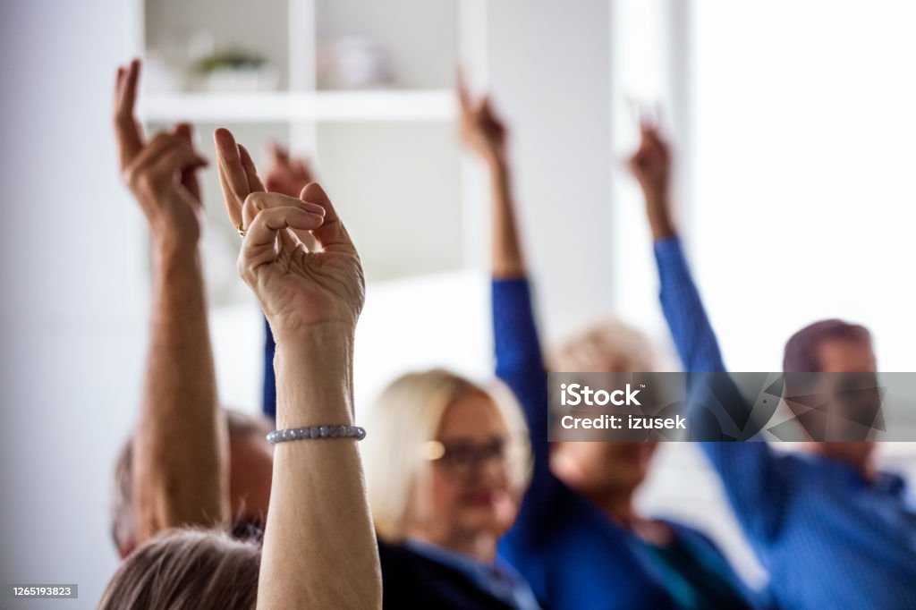 People voting during meeting in nursing home Senior people voting during group therapy, raising hands. They are discussing about mental wellbeing. Close up of hands. Voting Stock Photo