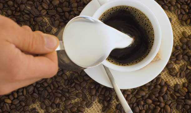 istock Hand pouring milk into coffee 1265193850