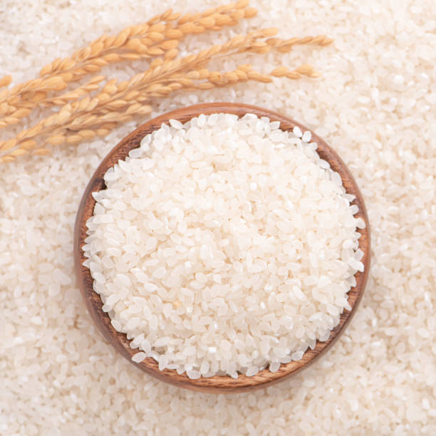 istock Raw rice in a bowl and full frame in the white background table, top view overhead shot, close up 1265193964