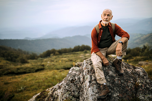 Senior hiker posing on the mountain rock