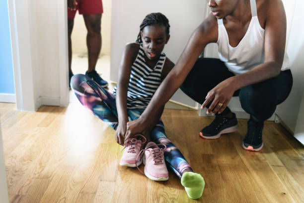 istock mother helping her daughter putting on running shoe 1265197085