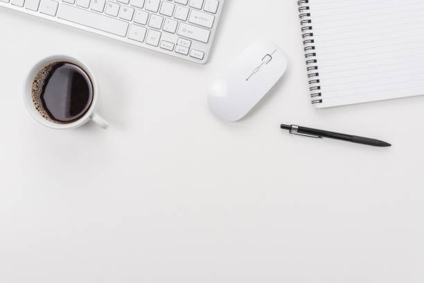 istock Workspace with computer keyboard, office supplies, and coffee cup on white background. Top view with copy space. 1265198499