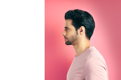 Close up profile view portrait of handsome man on geometric pink white background