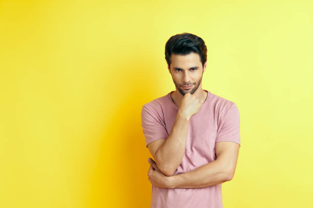 istock Young thoughtful man thinking and looking to camera with copy space, isolated on yellow background 1265200717