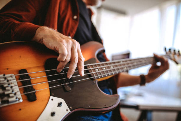 Senior musician playing bass guitar in a music studio