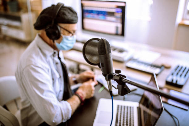 istock Senior radio host in his home office with a face mask 1265201851