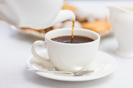 Verter té inglés caliente en la taza de té de cerámica blanca photo