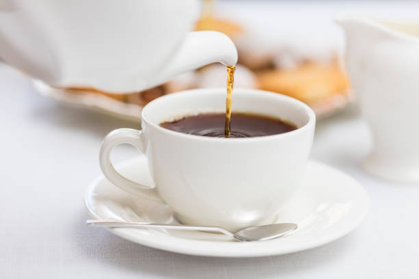 verser le thé anglais chaud dans la tasse de thé en céramique blanche - tea cup afternoon tea tea teapot photos et images de collection