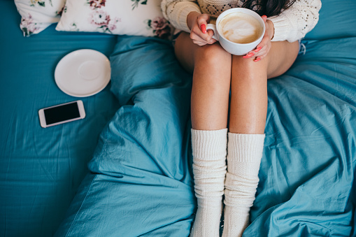 Woman drinking morning coffee in bed