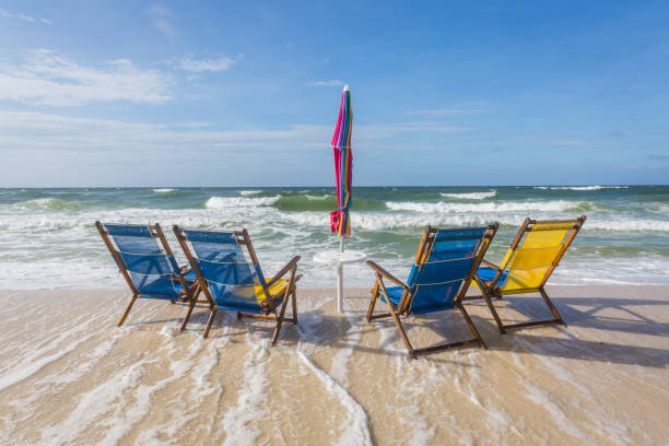 four empty beach chairs being overtaken by incoming tide - overtaken imagens e fotografias de stock