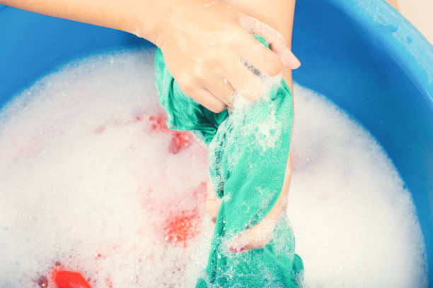 istock Woman use hands washing color clothes in basin 1265209247