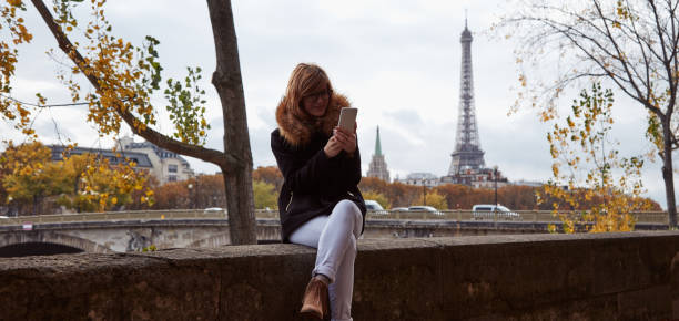 istock Girl using cellphone with Paris city background, Seine river and Eiffel tower. 1265210396