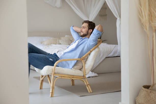 istock Satisfied calm young man relaxing stretching on cozy chair 1265210556