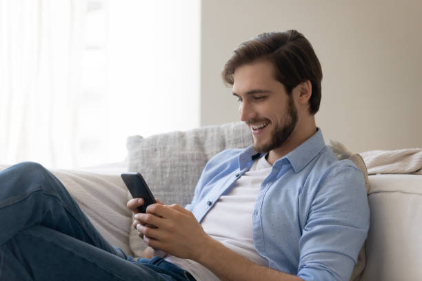 istock Smiling cheerful young man using smartphone, surfing internet, chatting online 1265210561