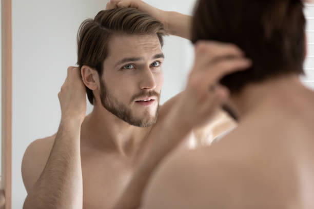 istock Close up anxious young man touching hair, looking in mirror 1265210562