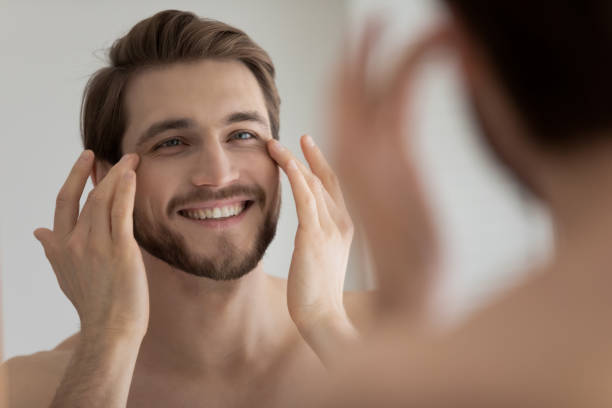 istock Close up mirror reflection smiling man touching skin under eyes 1265210563