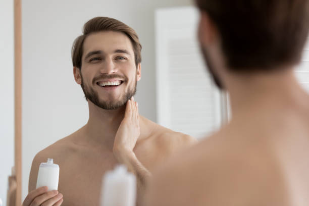 istock Close up mirror reflection overjoyed young man applying aftershave lotion 1265210565
